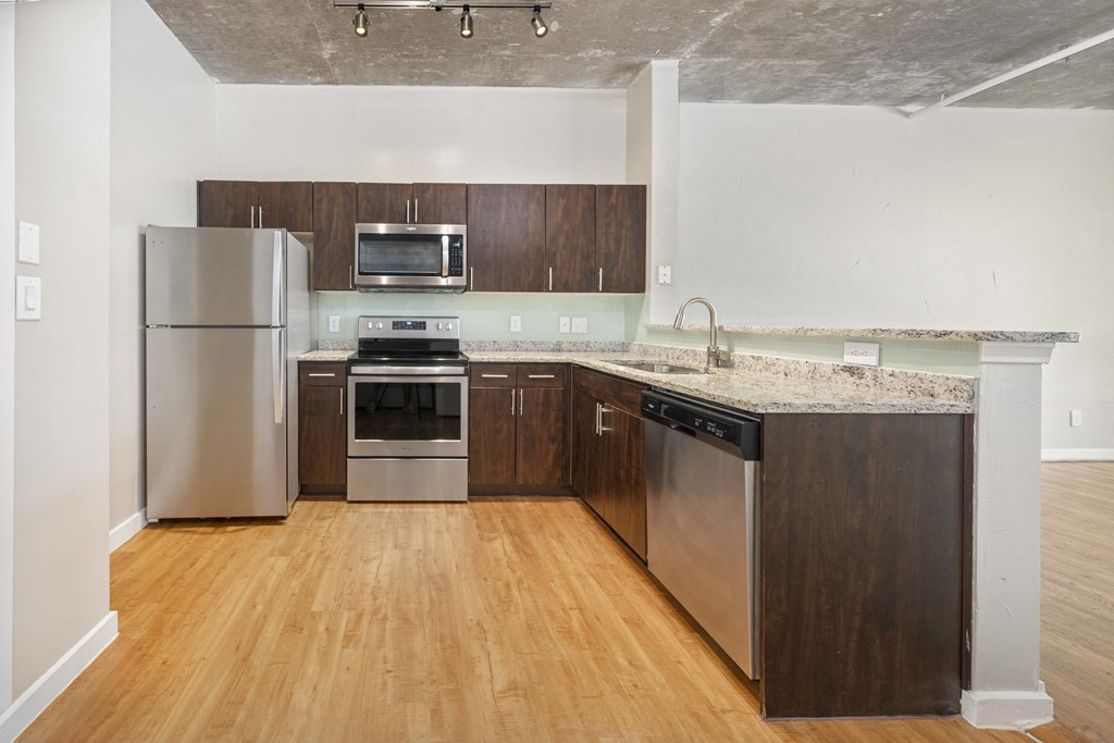 an empty kitchen with wooden floors and stainless steel appliances